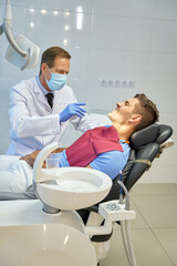 Professional dental surgeon conducting medical check-up for young man