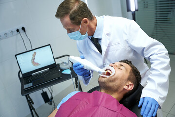 Tech-smart doctor inspecting patient teeth with special device