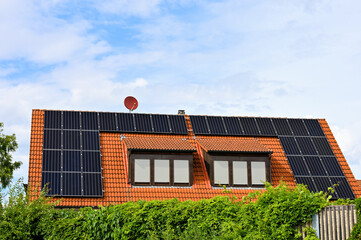 Solarzellen auf rotem Hausdach zur Erzeugung von grünem Strom