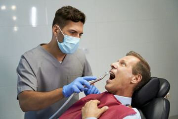 Fototapeta premium Certified dentist treating his patient at the clinic