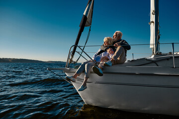 Happy retired family couple relaxing on a sail boat or yacht deck floating in a calm blue sea,...