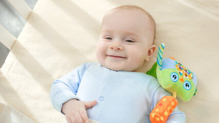 Portrait of happy smiling baby boy lying in crib at morning