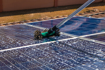 Solar worker cleaning photovoltaic panels with brush and water. Photovoltaic cleaning, before and after concept  image. Space for text.