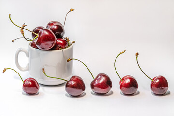 Fototapeta na wymiar sweet cherries in a porcelain cup on a white surface