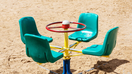 hand driven carousel on city yard sandy playground closeup