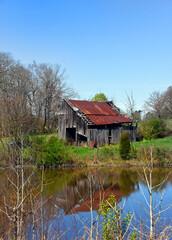 Barn and Sky Reflect in Still Water of Farm Pond