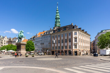 busy city street in downtown Copenhagen on a beautiful summer day with the Danish king's statue in the center