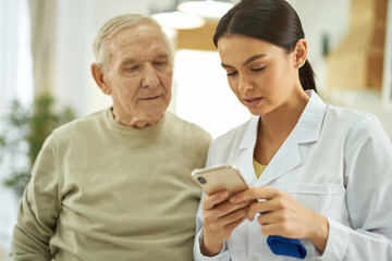 Nurse and senior citizen looking at mobile phone screen