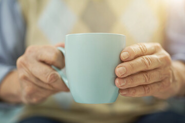 Aged man resting at home with a cup of hot drink