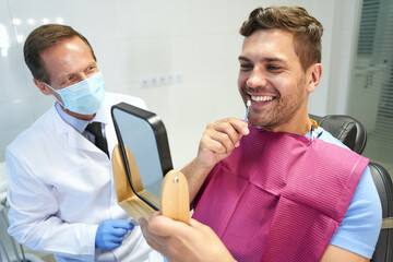 Young man trying enamel samples from teeth whitening kit