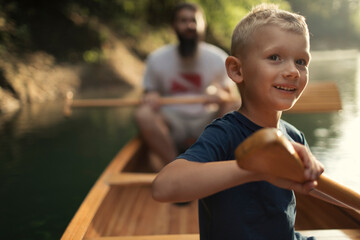 Cute boy canoeing on the lake with his dad
