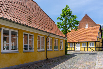 yellow buildings and half-timbered hosues on a cobblestone street in the historic old town center of Svendborg
