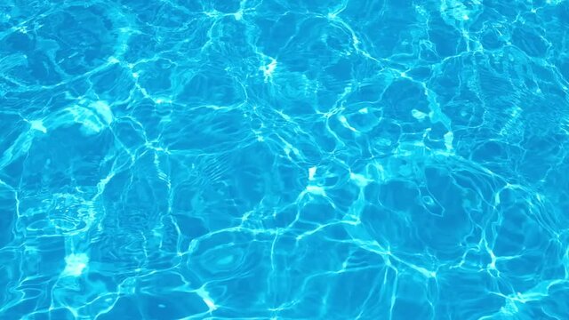 Pure transparent blue water in the swimming pool with light reflections. HD resolution video. Slow motion Texture of water in swim pool