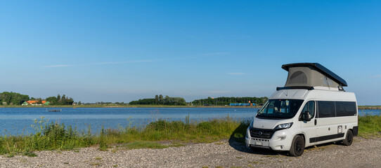 gray camper van parked on a gravel road at the ocean shore of Lolland Island in southern Denmark