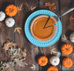 Overhead view of pumpkin pie surrounded by mini pumpkins on rustic wooden table