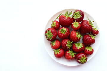 Strawberries on a plate. Fresh organic summer red berries on white background. Top view, copy space