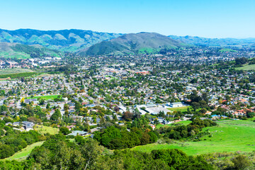 Elevated scenic view of San Luis Obispo urban area sprawl and green mountains of Santa Lucia Range from Bishop Peak Trail on sunny spring day