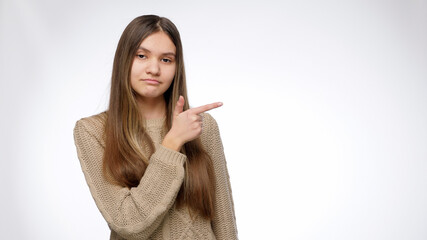 Confident smiling girl pointing with index finger on her side. Place your product or object. Advertising template.