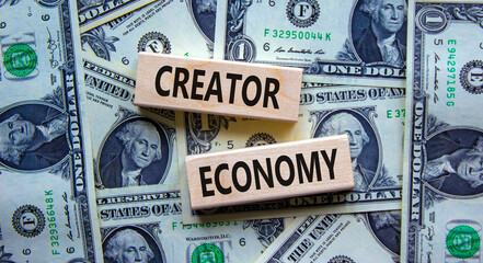 Creator economy symbol. Wooden blocks with words Creator economy on beautiful background from dollar bills, copy space. Business and creator economy concept. - obrazy, fototapety, plakaty