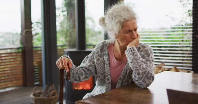 Senior mixed race woman leaning on walking cane and thinking