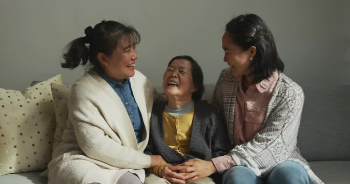 Smiling senior asian woman with two adult daughter and granddaughter embracing