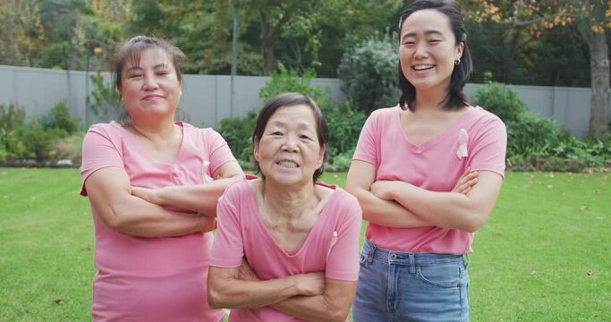 Portrait of smiling asian adult granddaughter, mother and grandmother standing in garden smiling