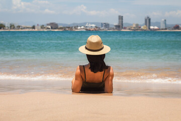 Fototapeta na wymiar young latin woman at the beach wearing a summer hat