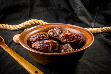 Big luxury dried date fruit in bowls on the dark surface, kurma ramadan kareem concept, close up.