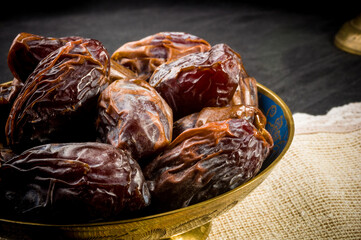 Big luxury dried date fruit in bowls on a linen napkin, kurma ramadan kareem concept, close up.