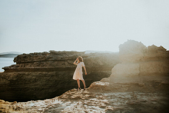 Faceless woman standing on rocky seacoast