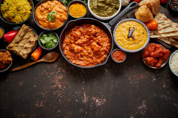 Assortment of various kinds of Indian cousine on dark rusty table