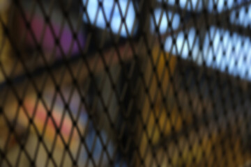 Defocused wire mesh barrier with blurred light background. 