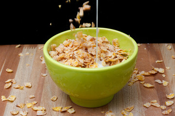 Green bowl with cereal and milk on a wooden table