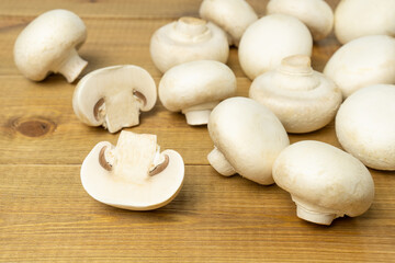 Fresh white mushrooms champignons on wooden table.