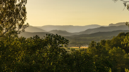 A picturesque landscape view of landscape and the hazy Pyrenees mountains in the background during sunset near Beziers, France