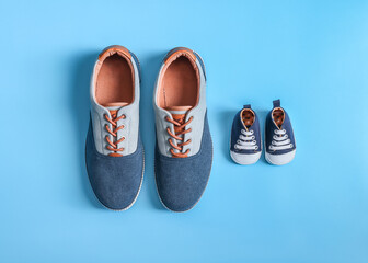 Shoes for men and children.
Men's and children's sneakers lie in the middle on a blue background, close-up top view.