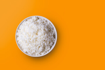 The rice was cooked in a white dish laying on an orange background with light coming in from the...