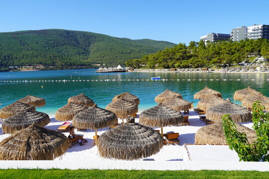 Bodrum, Turkey - August, 2020 Hotel Lujo, Beautiful Aegean sea turquoise blue color and palm trees on the beach. Sun loungers and umbrellas for tourists, Lux tourism concept 