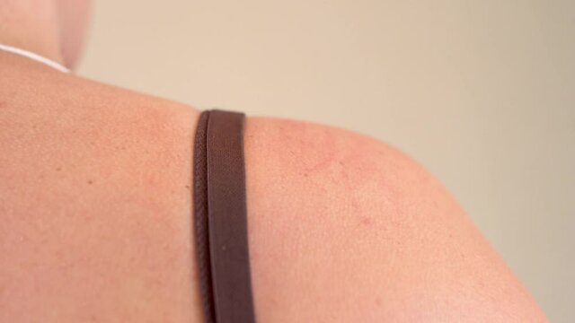 An adult woman straightens her bra strap. Underwear. Woman's shoulder. Manicure on the hand. Plump body. Buying linen. Fitting. Change of clothes. Romantic date. Part of the body. Close-up.