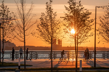 Silhouettes of people walking along the embankment