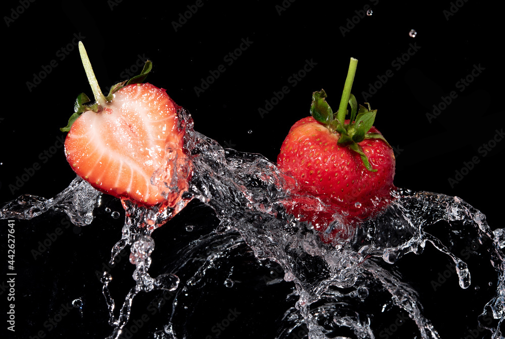 Poster Fresh strawberries in the air water splash on black background