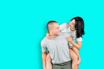 Happy couple playing a piggyback ride on studio