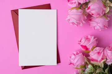 Blank paper with flowers placed on a pink background