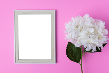 Photo frames and flowers placed on a pink background.