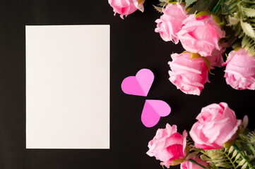 White paper and pink flowers pasted on a black background