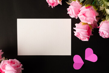 White paper and pink flowers pasted on a black background