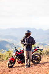 Young man standing on the side of his motorbike. Concept of freedom and enjoying the journey.