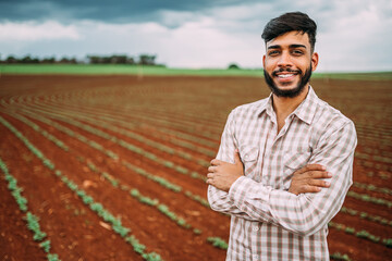 Young Latin farmer working on peanut plantation. Brazilian farmer looking at camera.