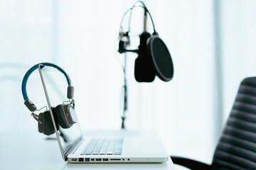 Fototapeta na wymiar Professional wired condenser microphone and headphones in audio studio close up.