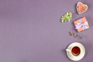 Fototapeta na wymiar Gift box, cup of black tea, dry flowers on purple background. flat lay, top view, copy space